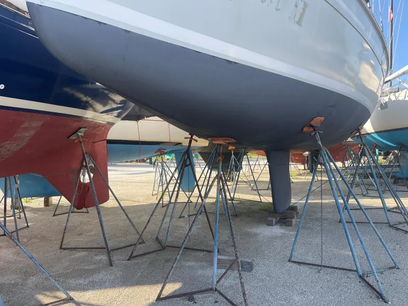 Slide: The Image of 2004 Hunter 44 Deck Salon sailboat, rear view, docked with equipment visible. - 2