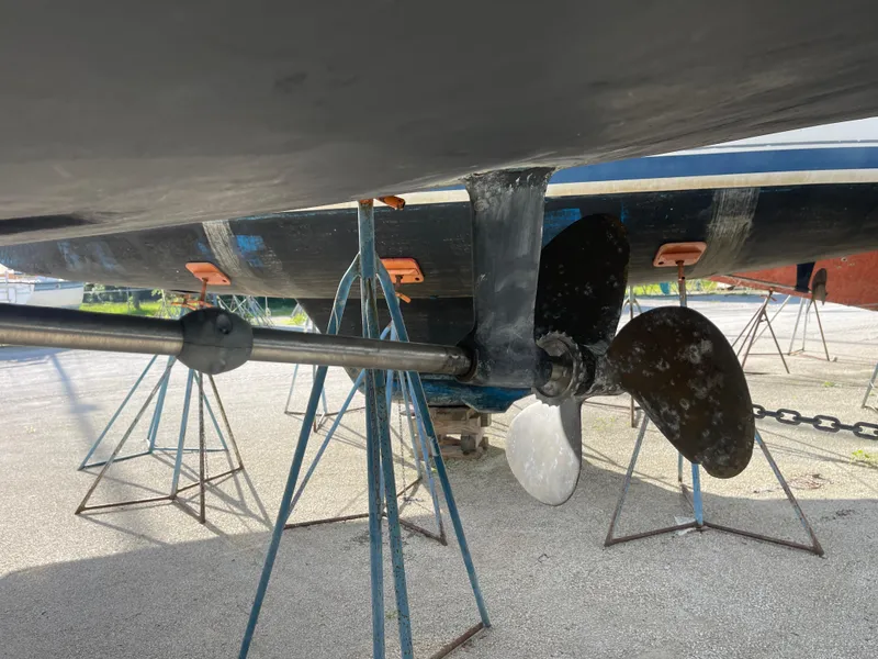 Slide: The Image of 2004 Hunter 44 DS Deck Salon sailboat on stands in a boatyard, with a car nearby. - 4