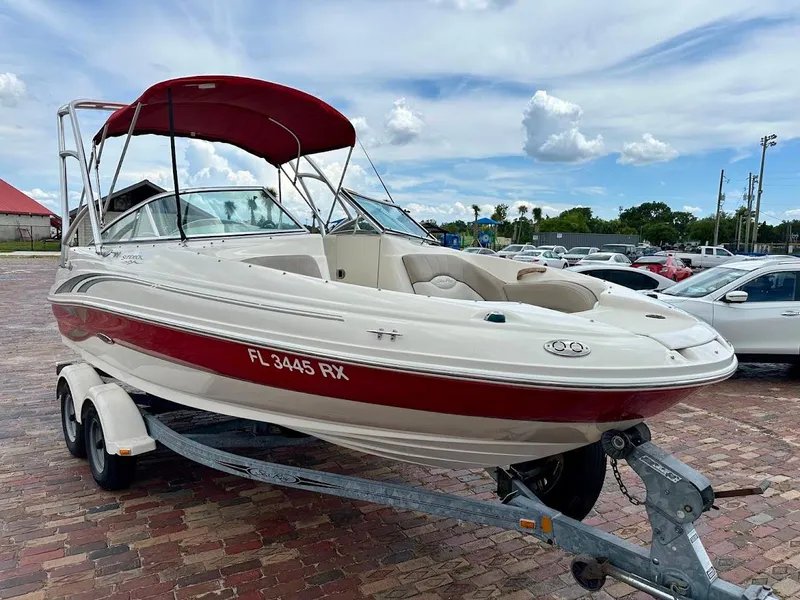 Slide: The Image of 2004 Sea Ray SunDeck 200 boat with red canopy on a trailer, parked outdoors. - 1