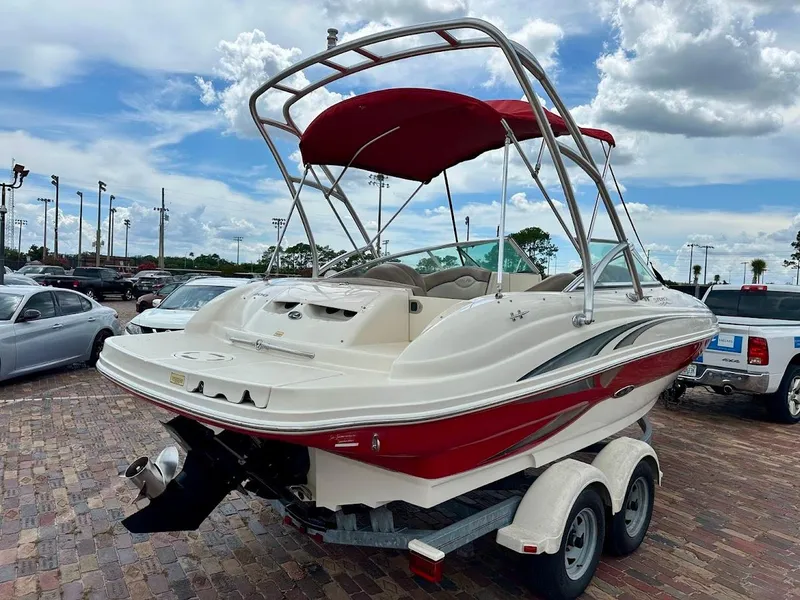 Slide: The Image of 2004 Sea Ray SunDeck 200 boat with red canopy on a trailer, parked outdoors. - 2