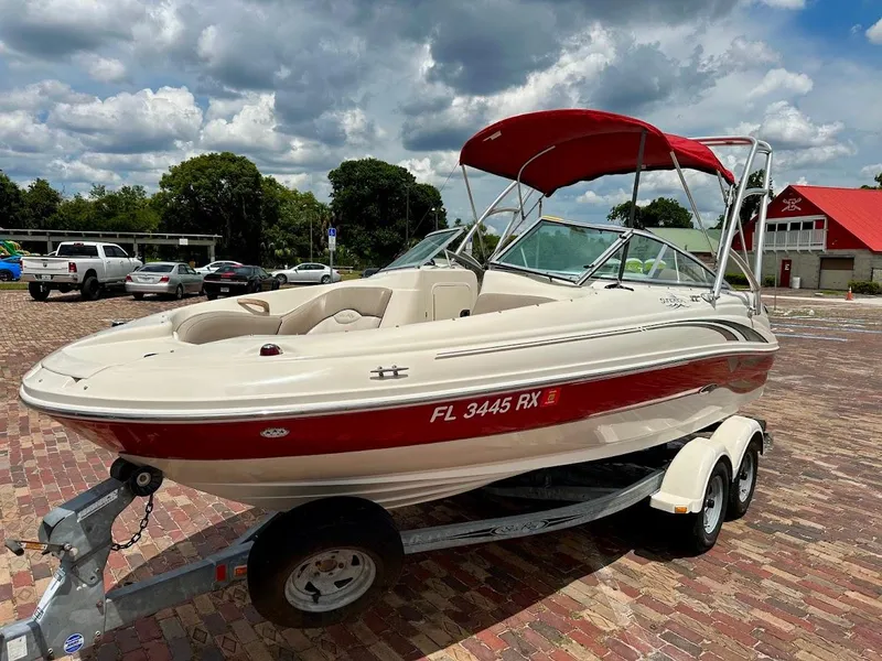 Slide: The Image of 2004 Sea Ray SunDeck 200 boat on trailer, red and white, parked on brick pavement. - 25