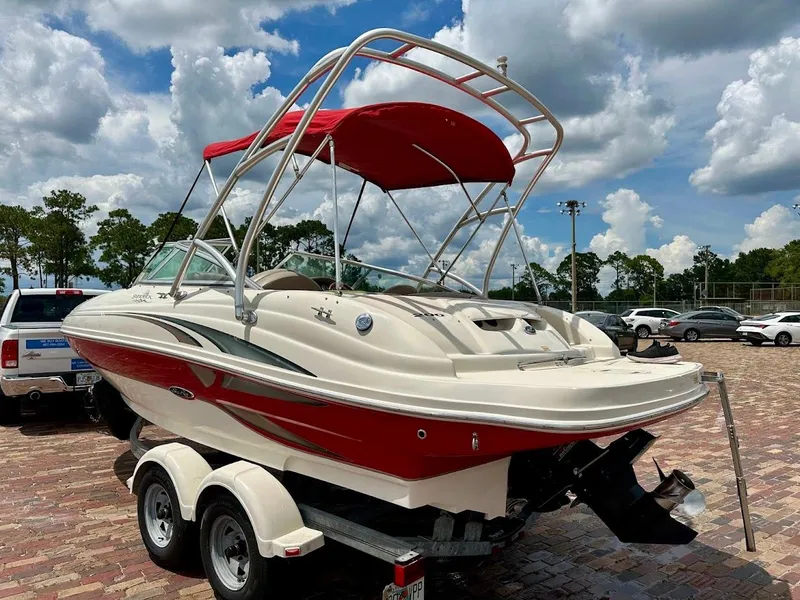 Slide: The Image of 2004 Sea Ray SunDeck 200 boat with red canopy on a trailer, parked outdoors. - 26
