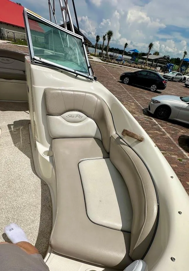 Slide: The Image of 2004 Sea Ray SunDeck 200 boat interior with beige seating, parked on a sunny day. - 36