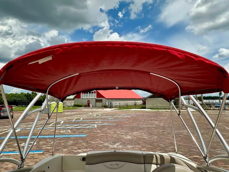 Slide: The Image of 2004 Sea Ray SunDeck 200 with red canopy, parked under a cloudy sky. - 38