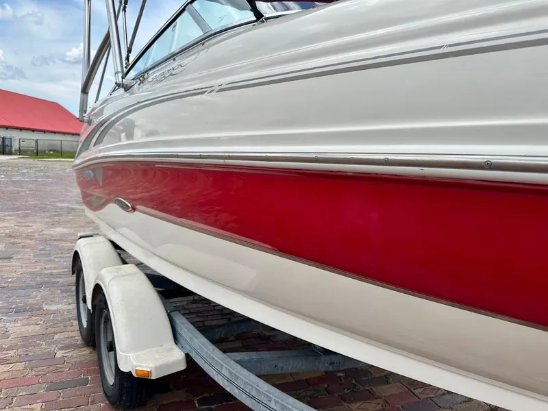 Slide: The Image of 2004 Sea Ray SunDeck 200 boat on trailer, featuring a red and white exterior. - 9