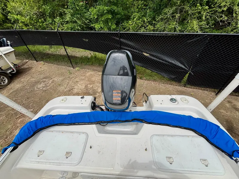 Slide: The Image of 2004 Sea Chaser 220 Bay Runner boat with outboard motor, parked near a fence. - 8