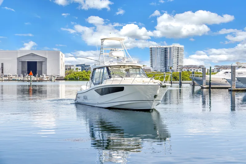 Slide: The Image of 2023 Boston Whaler 405 Conquest boat on calm water, with marina and buildings in background. - 12