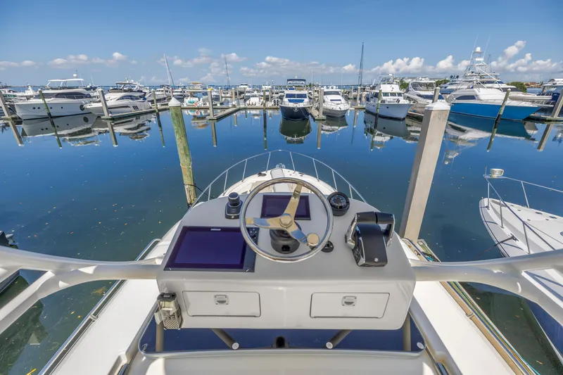 Slide: The Image of Helm of 2023 Boston Whaler 405 Conquest overlooking marina with docked boats. - 31