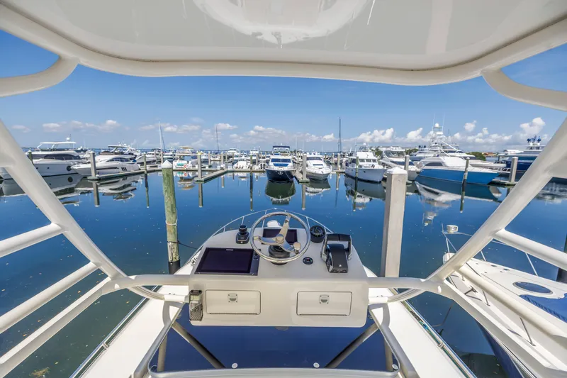 Slide: The Image of Boston Whaler 405 Conquest 2023 helm view at marina, surrounded by yachts and clear blue sky. - 32