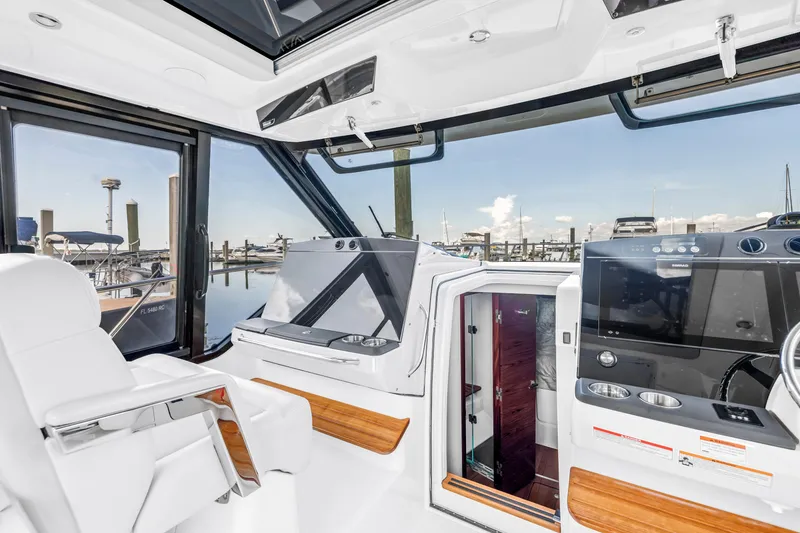 Slide: The Image of 2023 Boston Whaler 405 Conquest helm with modern controls and marina view. - 35