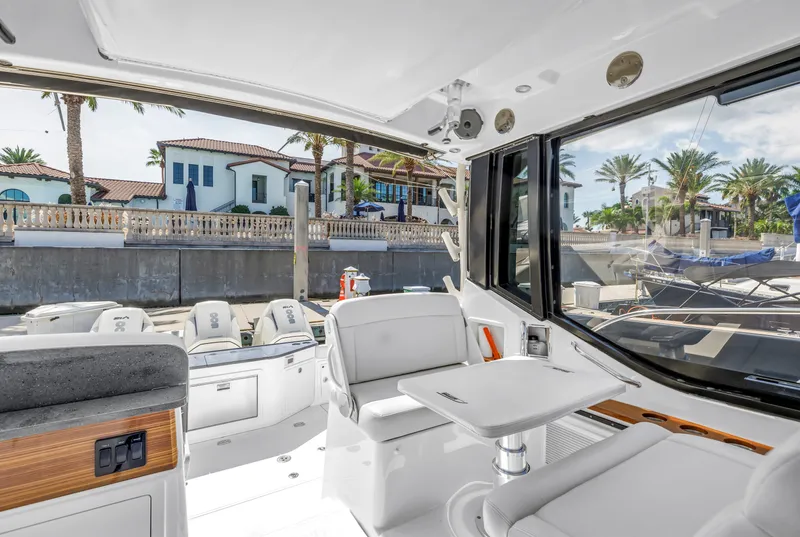 Slide: The Image of 2023 Boston Whaler 405 Conquest interior with seating and table, docked near luxury homes. - 41