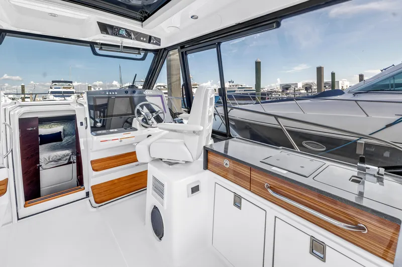 Slide: The Image of 2023 Boston Whaler 405 Conquest interior with helm, seating, and cabin view at marina. - 5
