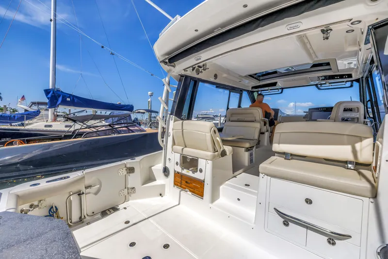 Slide: The Image of 2023 Boston Whaler 405 Conquest interior with seating, docked at marina under clear blue sky. - 9