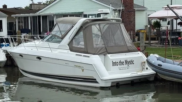 Slide: The Image of 2002 Formula 31 PC boat named "Into the Mystic" docked by waterfront homes. - 1