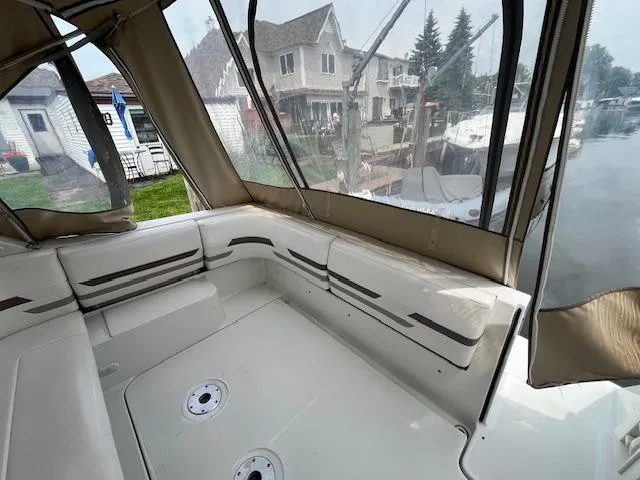 Slide: The Image of 2002 Formula 31 PC boat interior with beige seating and clear canopy, docked near waterfront homes. - 33
