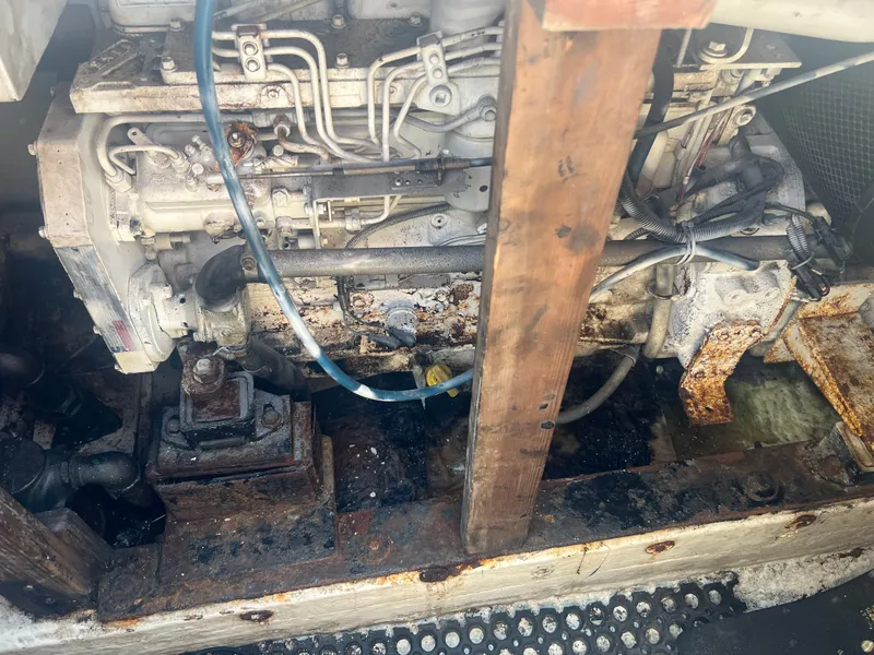 Slide: The Image of Rusty engine compartment of a 1984 JC 35 boat, showing mechanical components and wooden support. - 16