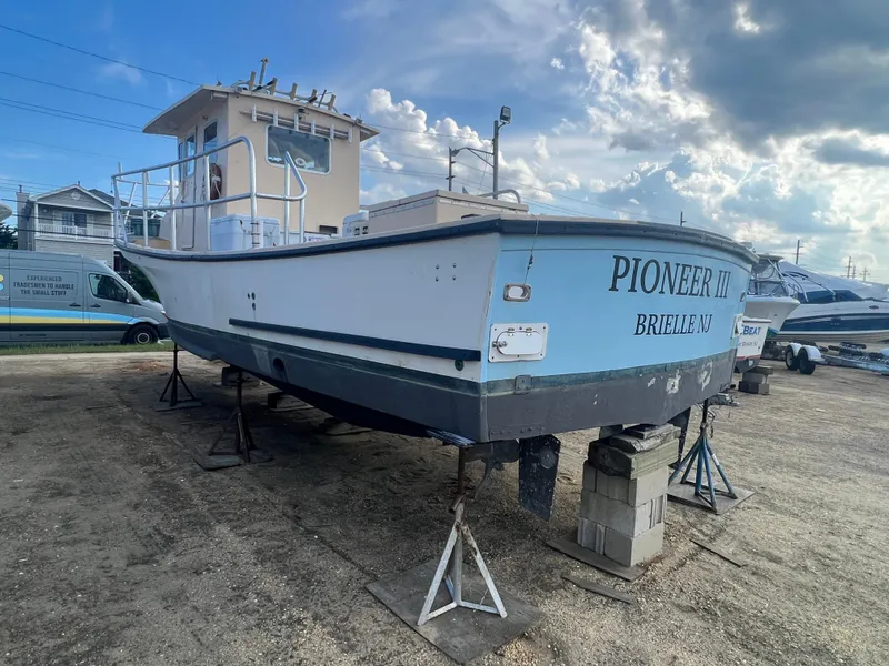 Slide: The Image of 1984 JC 35 boat "Pioneer III" on stands in Brielle, NJ, under a cloudy sky. - 5