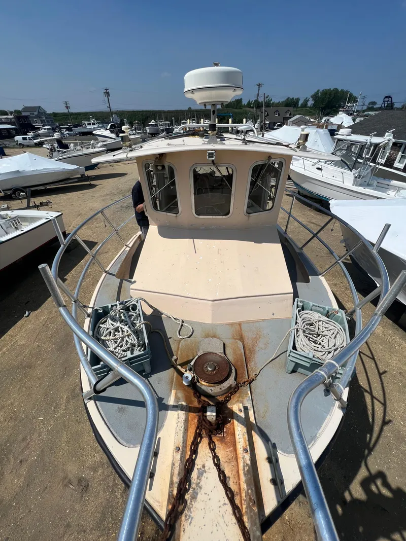 Slide: The Image of 1984 JC 35 boat with anchor and ropes, docked in a marina under clear blue sky. - 7