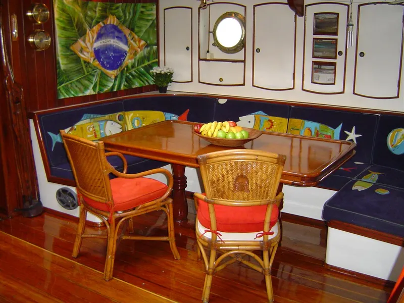 Slide: The Image of Interior of 1991 Custom Horacio Carabelli Schooner with wooden table, wicker chairs, and nautical decor. - 15