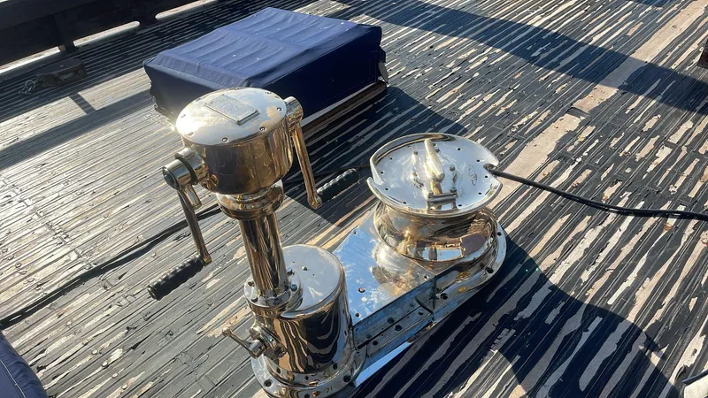 Slide: The Image of Polished winch on 1991 Horacio Carabelli Schooner deck, with blue cushion nearby. - 3