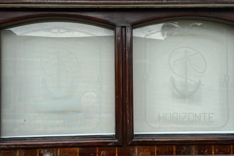 Slide: The Image of Wooden-framed windows with anchor design and "HORIZONTE" text on a 1991 Horacio Carabelli Schooner. - 39