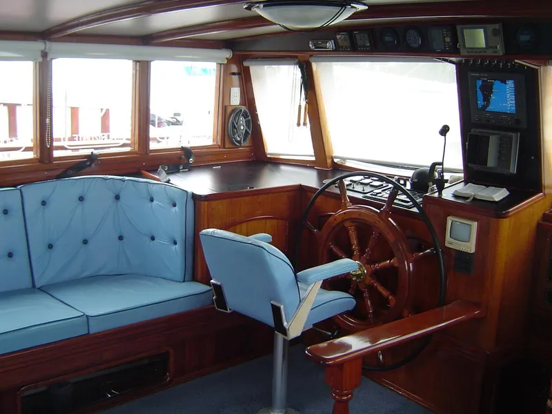 Slide: The Image of Interior of 1991 Custom Horacio Carabelli Schooner with blue seating and wooden steering wheel. - 7