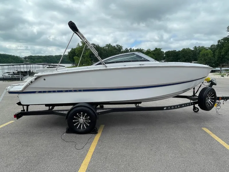 Slide: The Image of 2025 Four Winns H1 boat on trailer in parking lot near lake. - 1