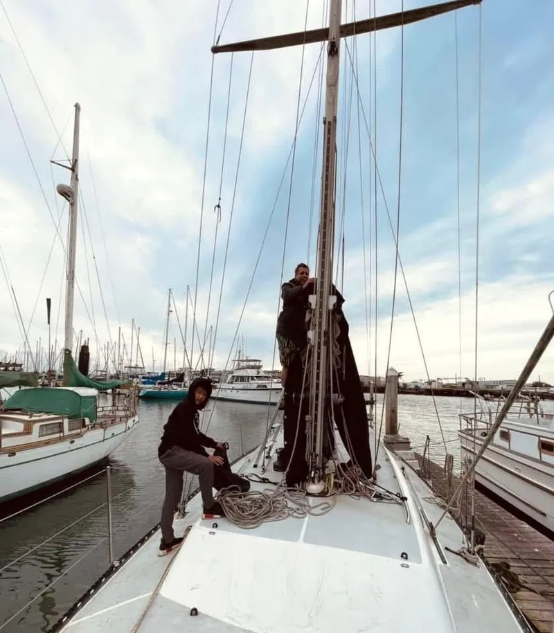 Slide: The Image of Two people working on a 1986 Santa Cruz 50 sailboat at a marina. - 2