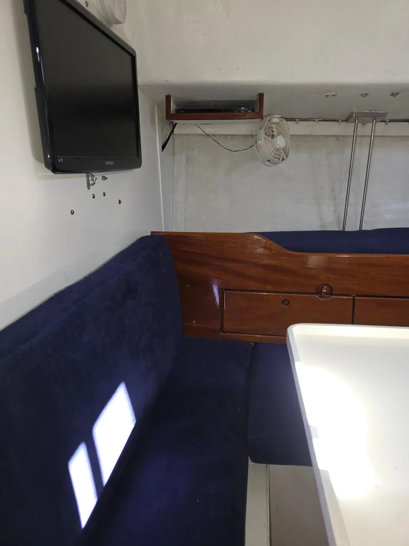 Slide: The Image of Interior of 1986 Santa Cruz 50 yacht with blue seating, wooden accents, and mounted TV. - 25