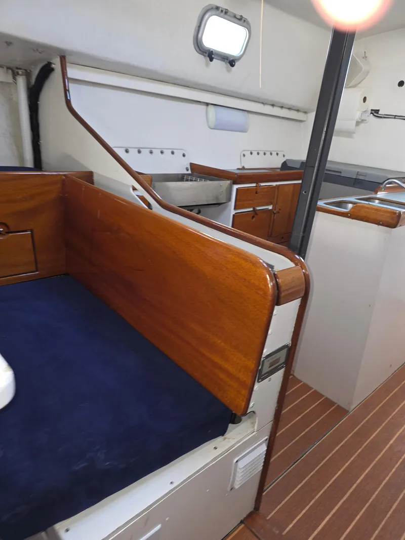 Slide: The Image of Interior of 1986 Santa Cruz 50 yacht with wooden finishes and compact kitchen area. - 26