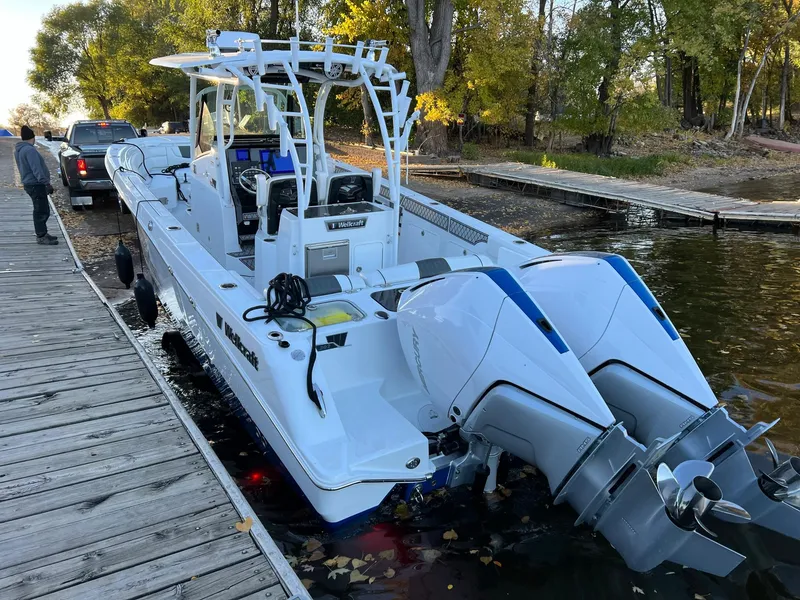 Slide: The Image of 2023 Wellcraft 302 Fisherman boat docked, featuring dual outboard engines and sleek design. - 15
