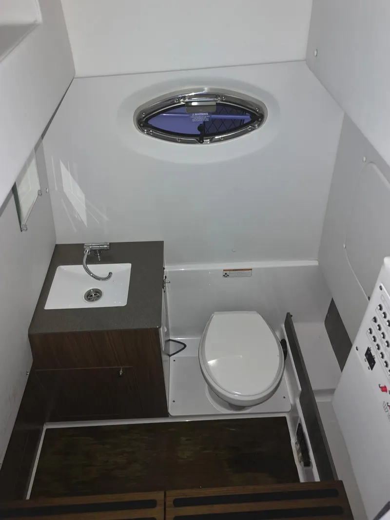 Slide: The Image of 2023 Wellcraft 302 Fisherman boat bathroom with sink, toilet, and porthole window. - 22