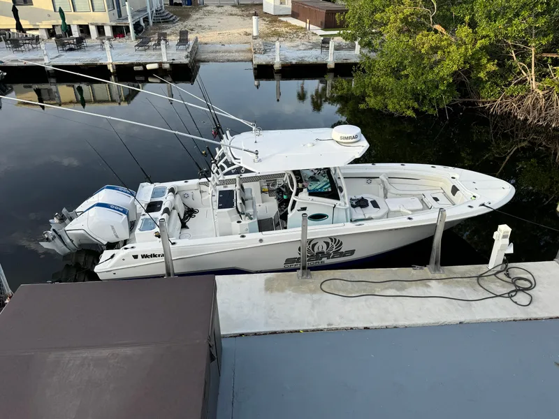 Slide: The Image of 2023 Wellcraft 302 Fisherman dashboard with navigation system and two beer bottles at sea. - 23