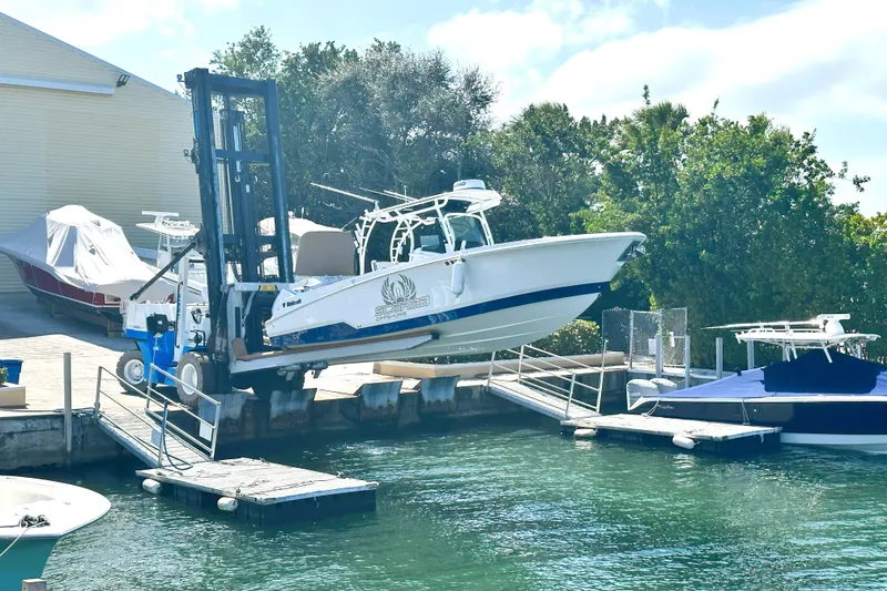 Slide: The Image of 2023 Wellcraft 302 Fisherman boat being lifted by a forklift at a marina. - 28