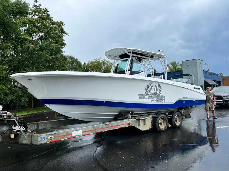 Slide: The Image of 2023 Wellcraft 302 Fisherman boat on trailer, parked outdoors with palm trees in background. - 7