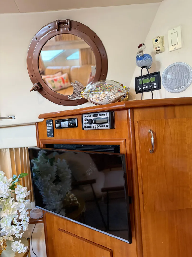 Slide: The Image of Interior of 2006 Carver 41 Cockpit Motor Yacht with TV, porthole, and decorative items. - 13
