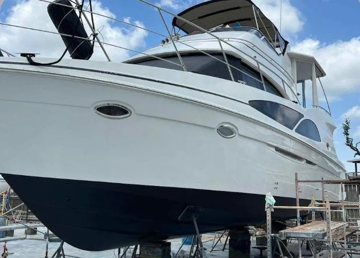 Slide: The Image of 2006 Carver 41 Cockpit Motor Yacht on dry dock, showcasing sleek design and structure. - 49