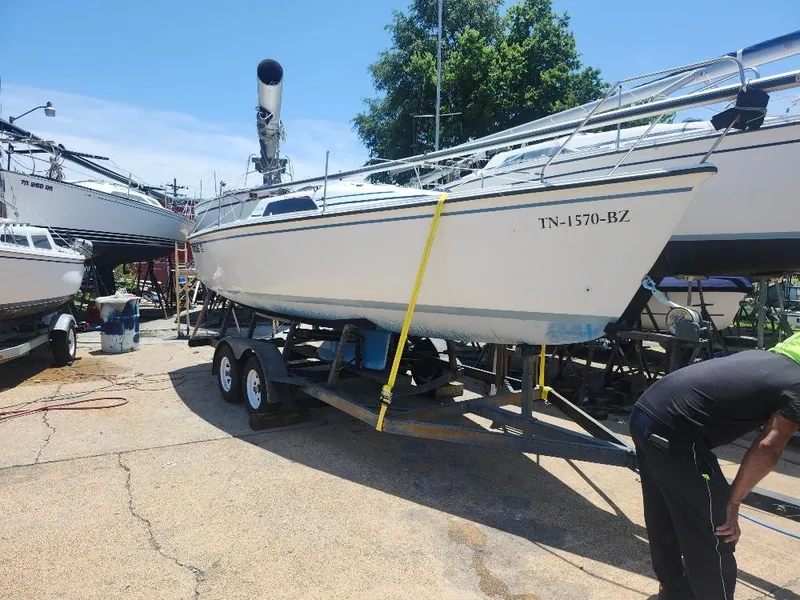 The Image of 1988 Hunter 23 sailboat on trailer, parked outdoors, with clear blue sky. - 0