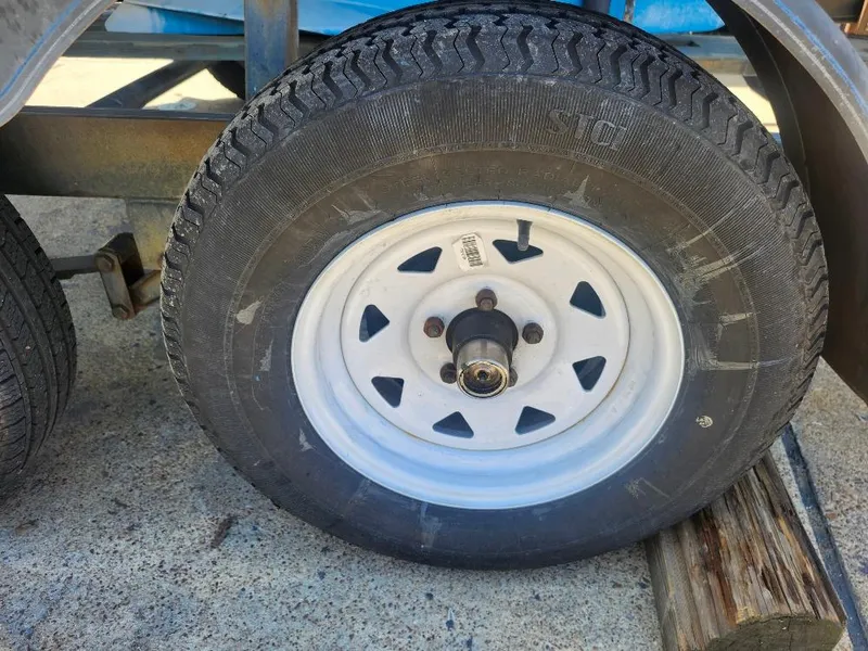 Slide: The Image of Trailer wheel on a Hunter 23, 1988 model, resting on a wooden block. - 12