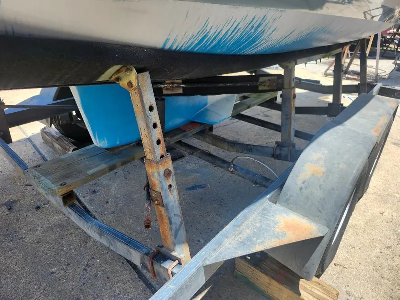 Slide: The Image of Rusty boat trailer supporting a 1988 Hunter 23 sailboat, showing blue hull and stabilizing jacks. - 14