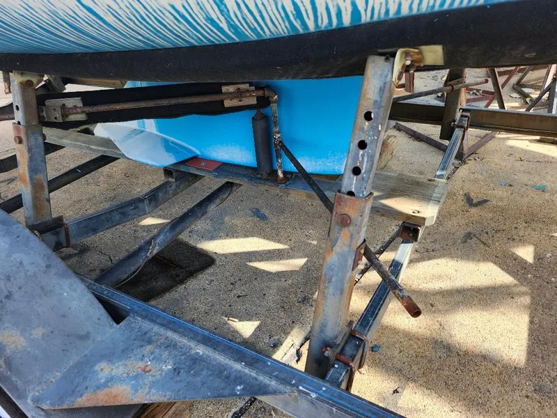 Slide: The Image of Rusty boat trailer supporting a blue 1988 Hunter 23 sailboat on a sandy surface. - 22