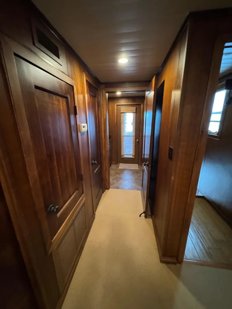 Slide: The Image of Wood-paneled hallway inside a 2003 custom houseboat, featuring carpeted flooring and a glass door. - 11