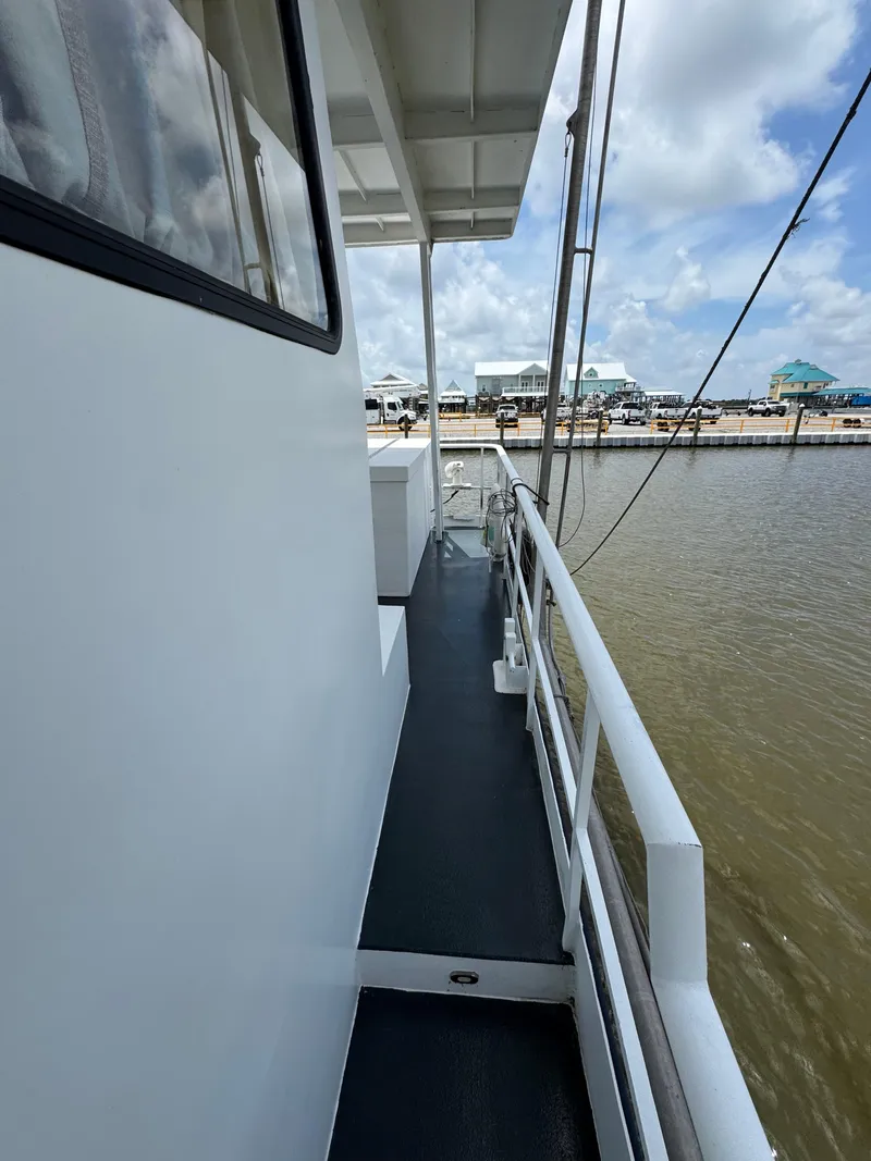 Slide: The Image of Custom 2003 houseboat deck with railing, docked by calm water under a cloudy sky. - 29