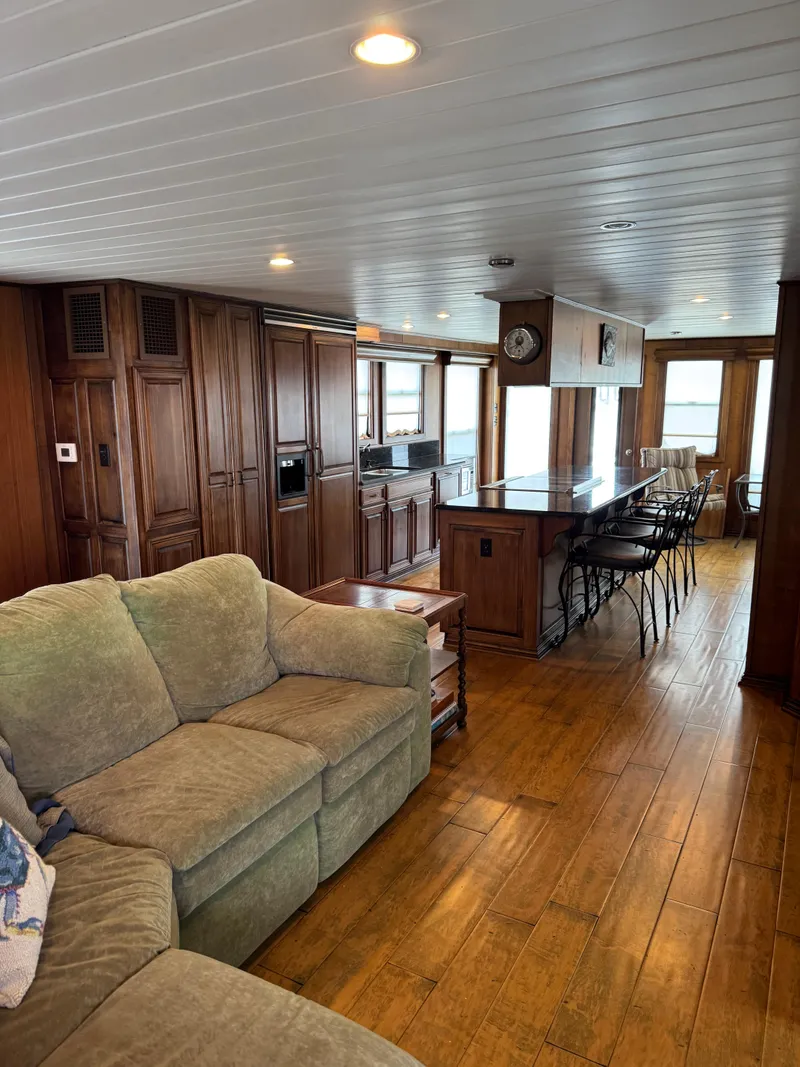 Slide: The Image of Luxurious 2003 custom houseboat interior with wooden flooring, cozy seating, and modern kitchen. - 4