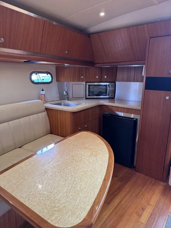 Slide: The Image of 2004 Tiara Yachts 3600 Sovran interior with kitchenette, dining area, and wood cabinetry. - 11