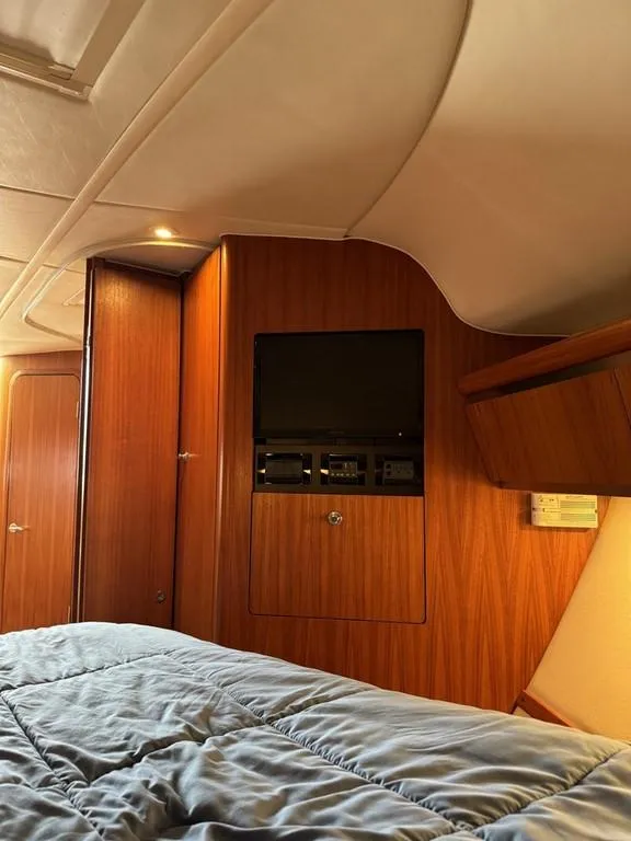 Slide: The Image of 2004 Tiara Yachts 3600 Sovran cabin interior with wood paneling and cozy bedding. - 22