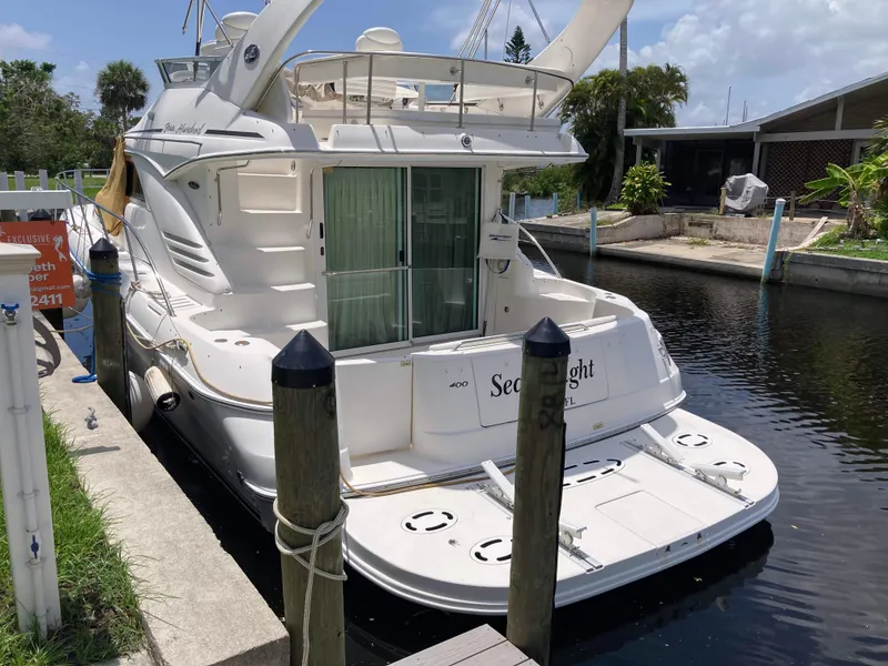 Slide: The Image of 2004 Sea Ray 400 Bridge Deck yacht docked in a serene canal setting. - 0