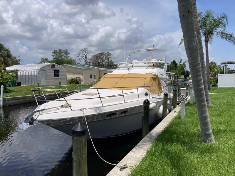 Slide: The Image of 2004 Sea Ray 400 Bridge Deck yacht docked by a canal under a cloudy sky. - 1