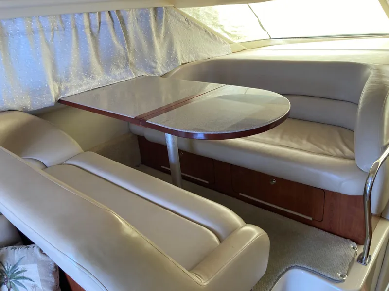 Slide: The Image of 2004 Sea Ray 400 Bridge Deck interior with beige leather seating and wooden table. - 19