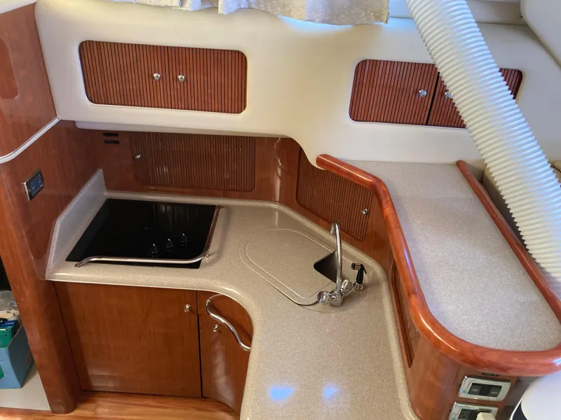 Slide: The Image of 2004 Sea Ray 400 Bridge Deck kitchen with wood cabinets and modern appliances. - 20